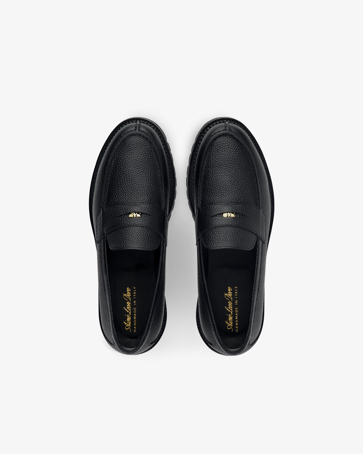 Top view of Lug Sole Queens Crest Loafer in black leather with gold insole text, shown on a light background.