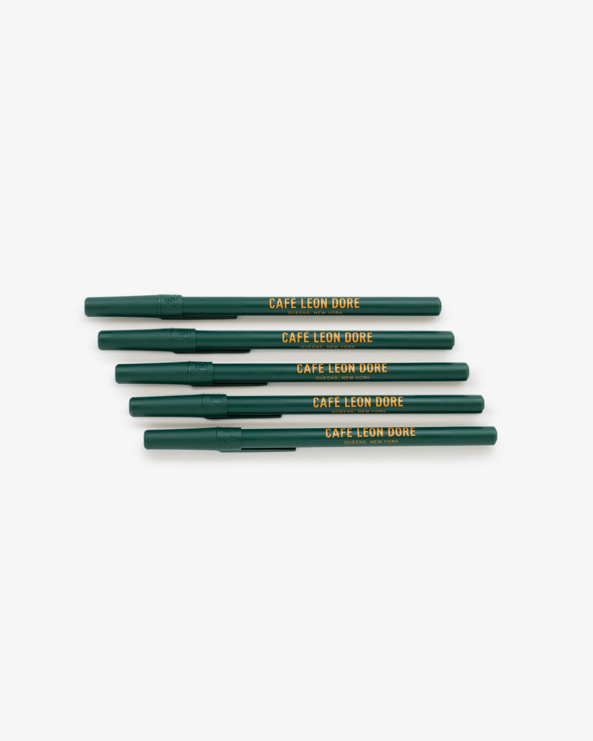 Five green Café Leon Dore Ballpoint Pens, yellow print, stacked in a row on a white background.