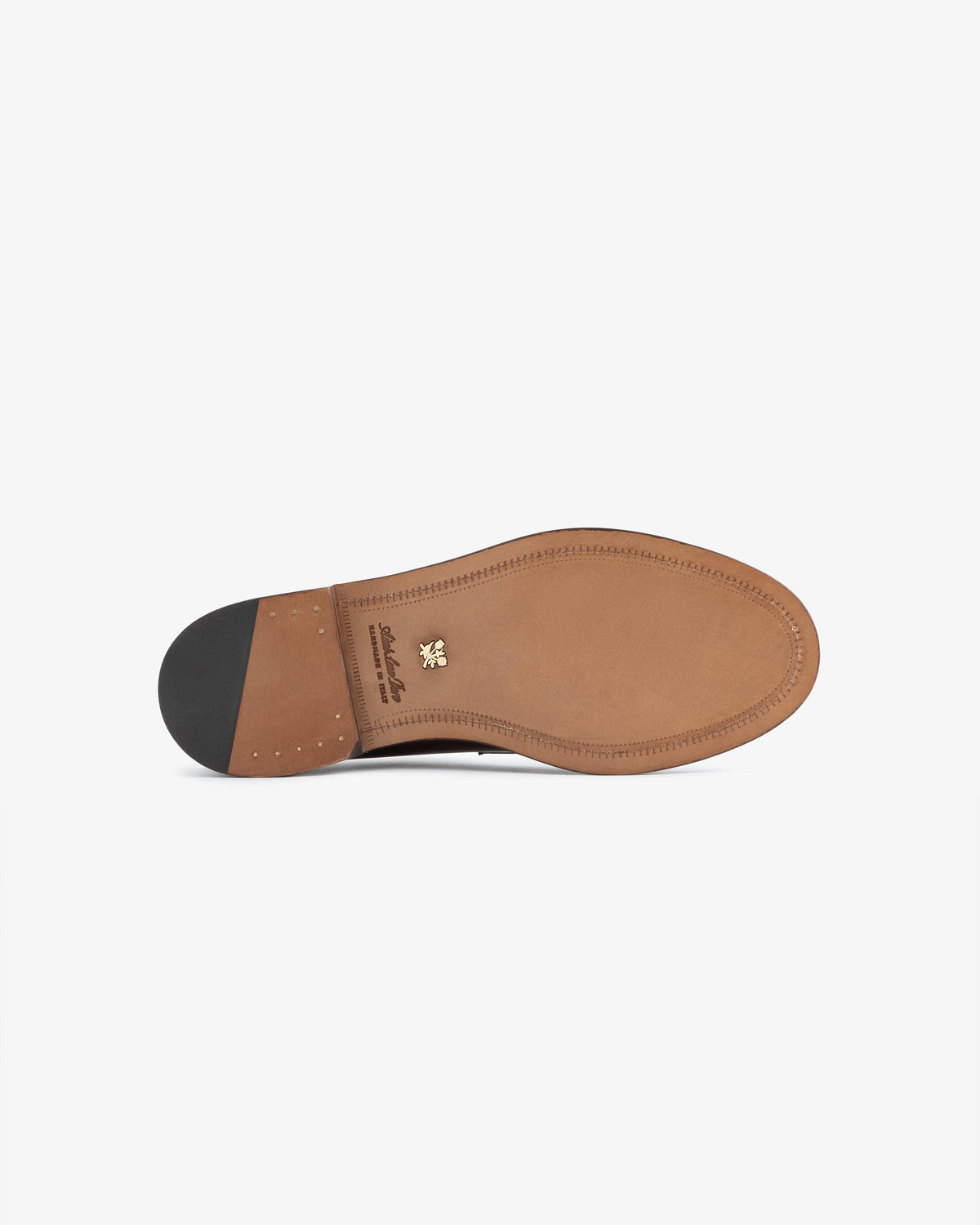 The image shows the tan leather sole of the Queens Crest Loafer with a black heel and gold emblem near the arch.