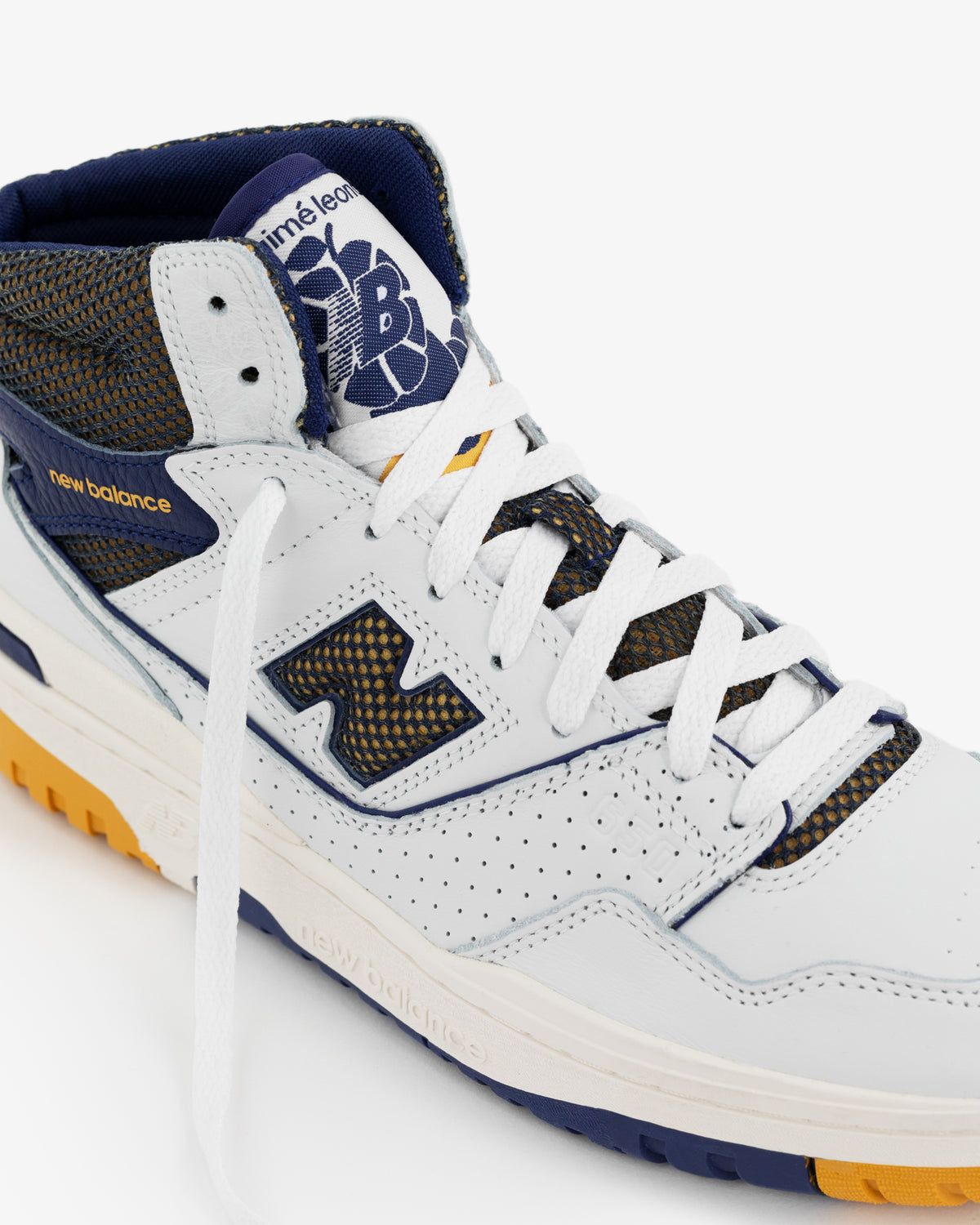 A close-up of the ALD / New Balance 650R sneaker in white with blue and yellow accents and a patterned tongue.
