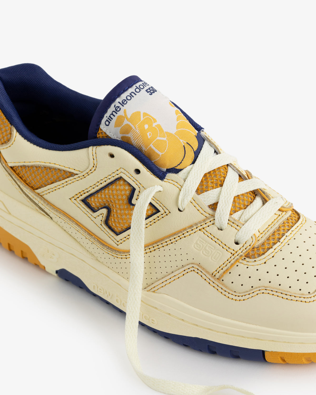 Cream and yellow ALD/NB P550 Oxfords with blue accents, bee graphic on tongue, and 550 on the side.