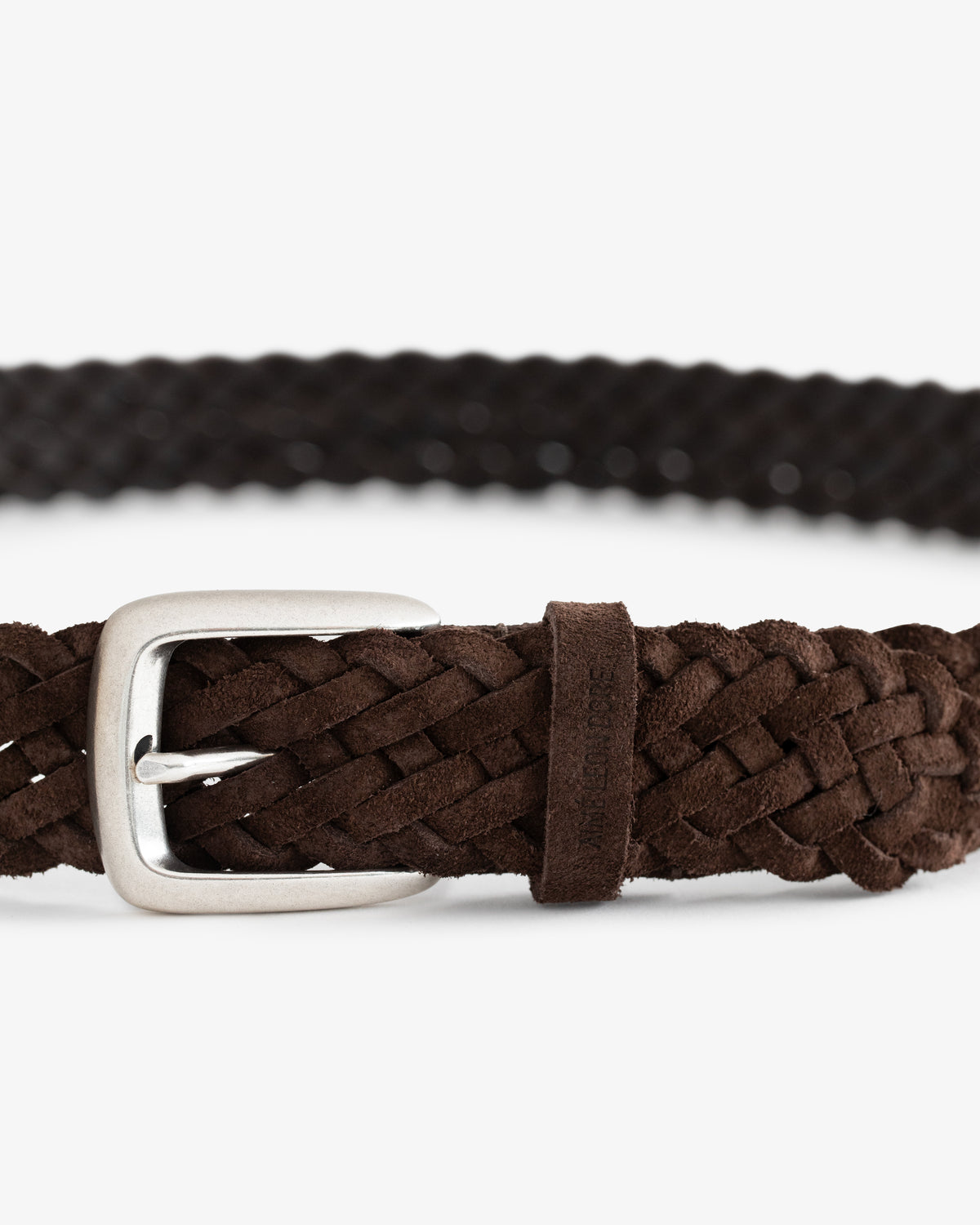 Close-up of the Braided Suede Belt in brown suede with a silver buckle, shown against a white background.