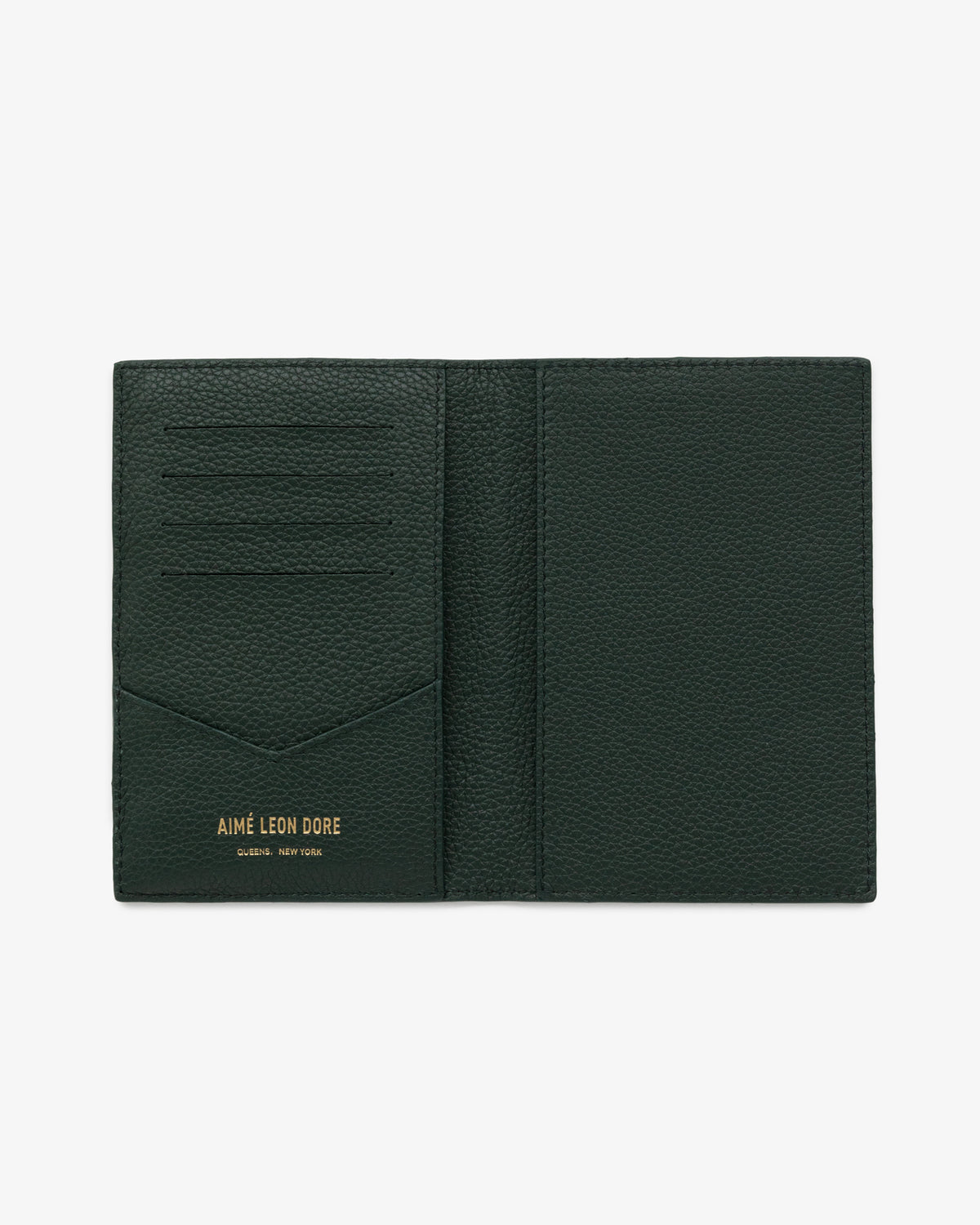 Dark green leather passport holder with card slots and gold AIMÉ LEON DORE QUEENS, NEW YORK text at the bottom.