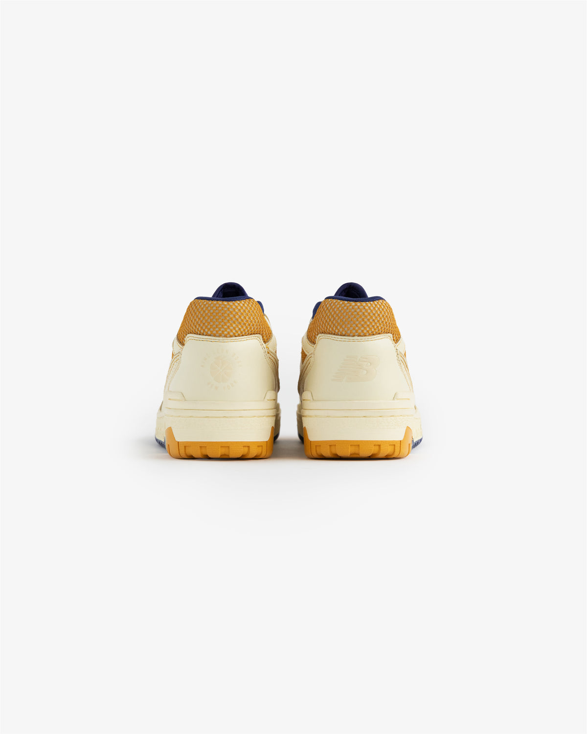 Rear view of ALD / NB P550 Basketball Oxfords in cream and yellow, rubber soles, on a plain white background.