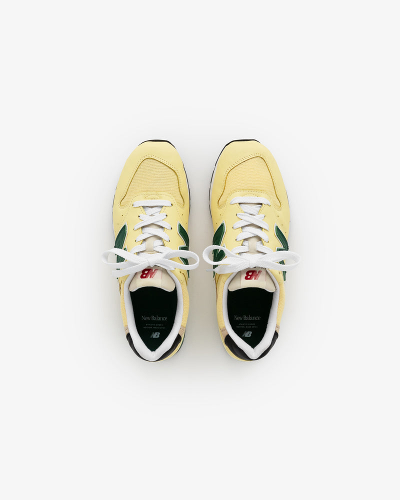 A pair of yellow and green New Balance Made in USA 996 sneakers viewed from above on a white background.