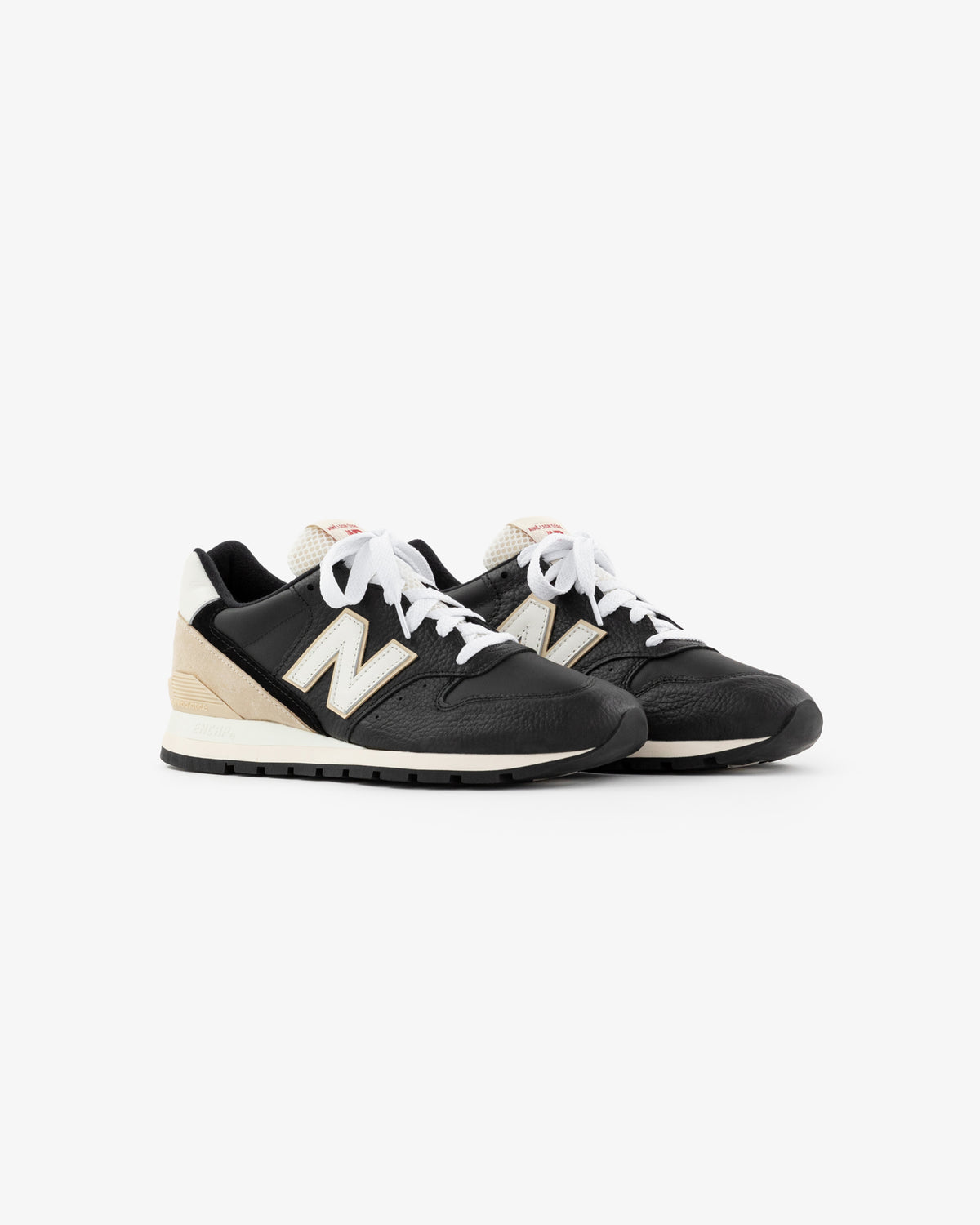 ALD / NB Made in USA 996 sneakers in black and beige with white laces and a white N logo on the side.
