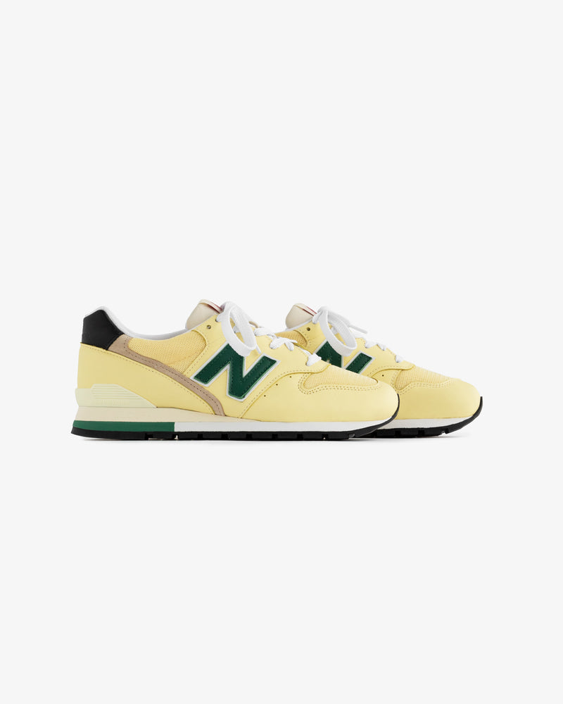 Yellow New Balance Made in USA 996 sneakers with green accents and white laces on a white background.
