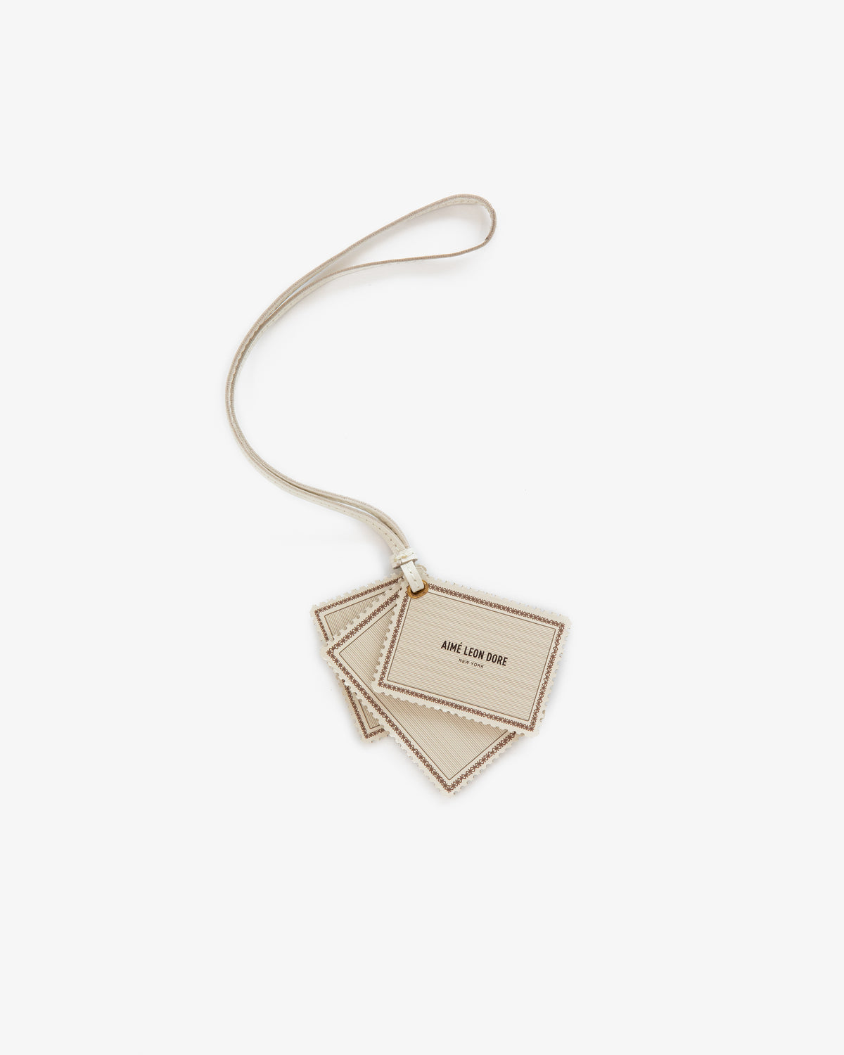 Beige Leather Traveler Charm with AIME LEON DORE text, attached to a matching strap, on a white background.