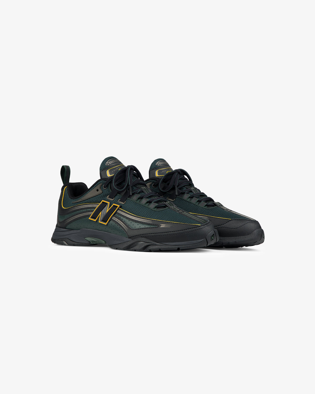 A pair of ALD / New Balance RC56 sneakers in dark green and black with yellow accents, on a white background.