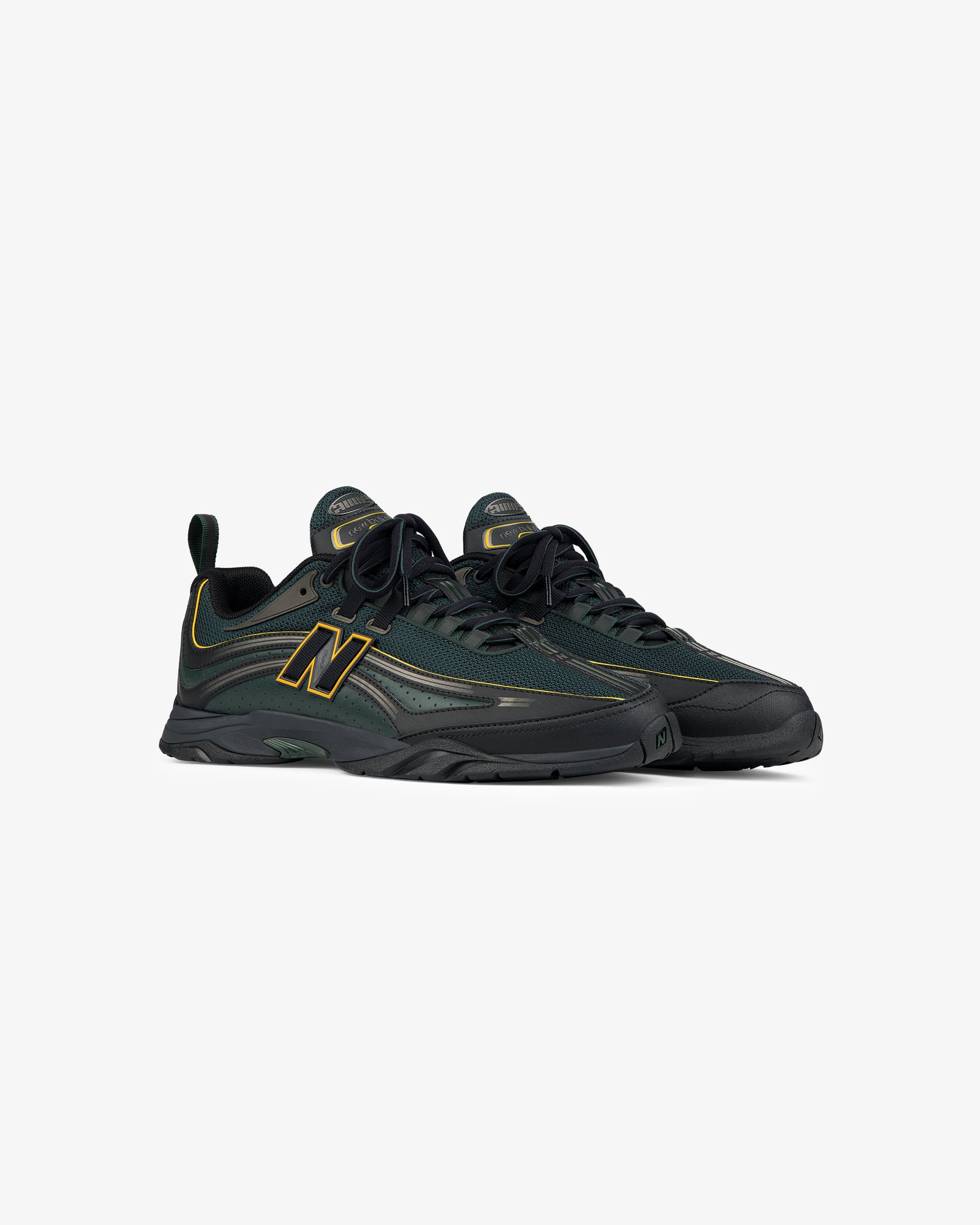 A pair of ALD / New Balance RC56 sneakers in dark green and black with yellow accents, on a white background.