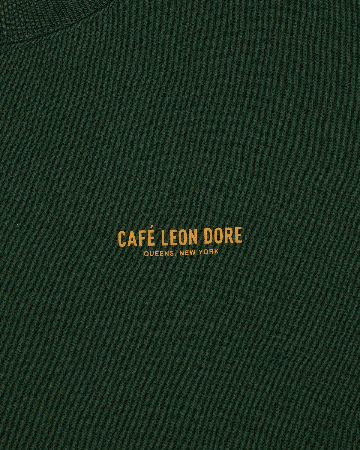 Dark green Café Leon Dore Crewneck Sweatshirt with yellow "CAFÉ LEON DORE QUEENS, NEW YORK" text at center.