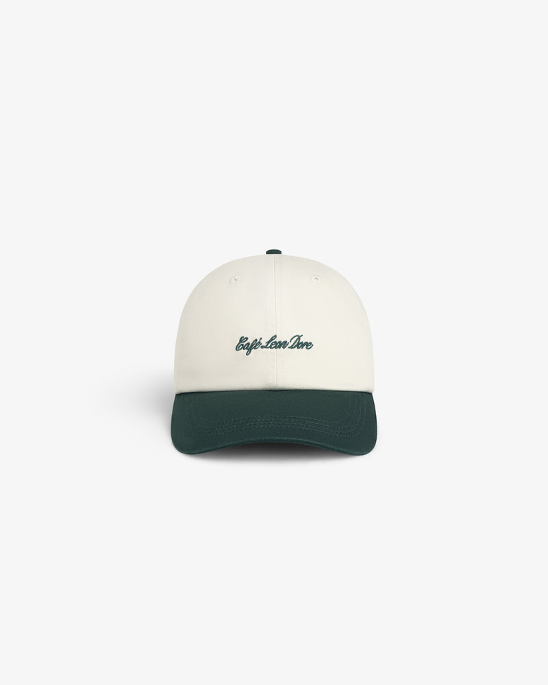 Café Leon Dore Script Hat: white cap with dark green brim, “trip.love.live” in green on front, white background.