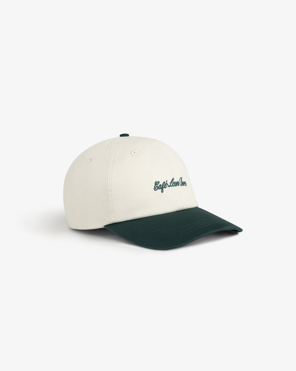 Café Leon Dore Script Hat: white cap, dark green brim, green “Café Leon Inn” embroidered on the front.