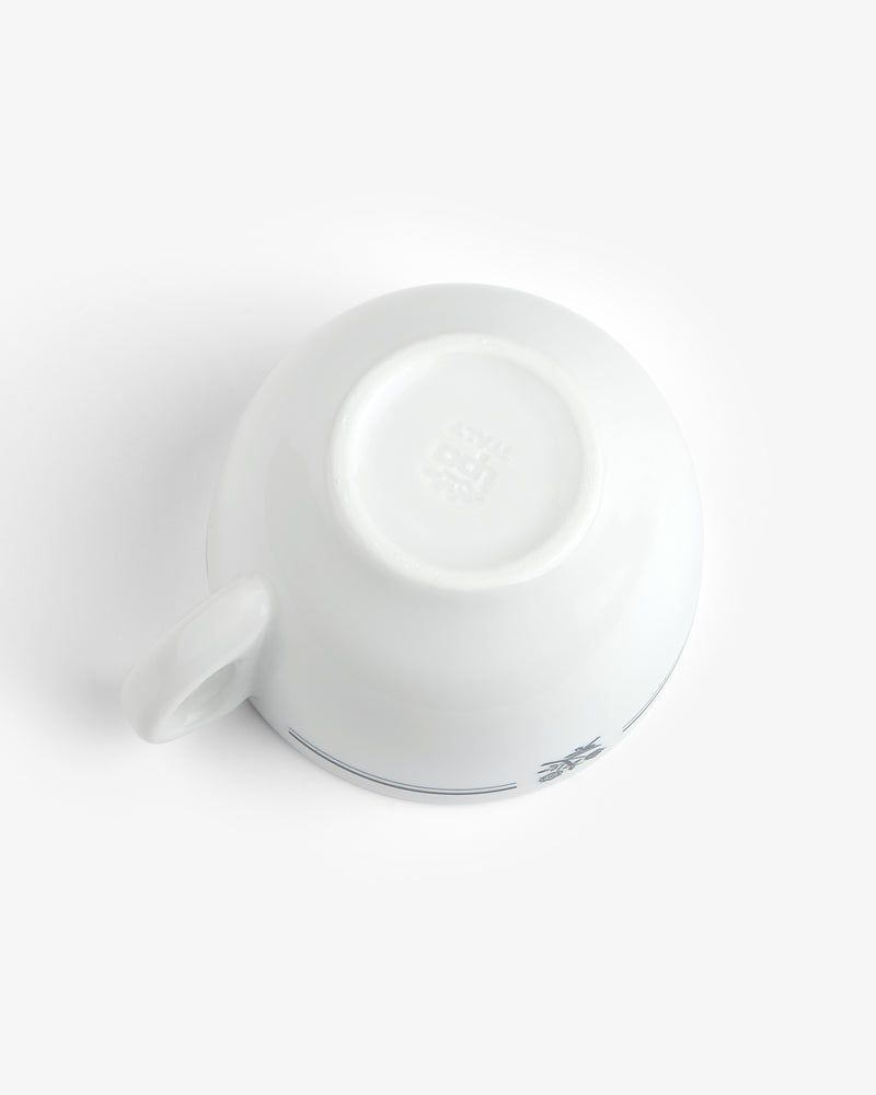 Café Leon Dore Cappuccino Cup & Saucer set, white ceramic cup upside down, handle shown left, plain background.