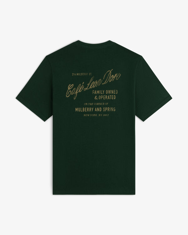 Café Leon Dore Mulberry Tee in dark green with gold “Family Owned & Operated” script on the back.