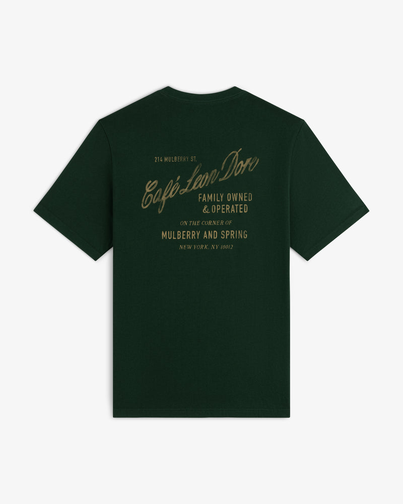 Café Leon Dore Mulberry Tee in dark green with gold “Family Owned & Operated” script on the back.