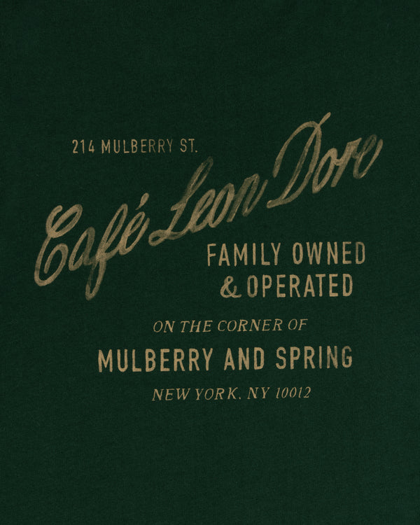 Green tee with gold text: Café Leon Dore, Family Owned & Operated, Mulberry and Spring, NYC.