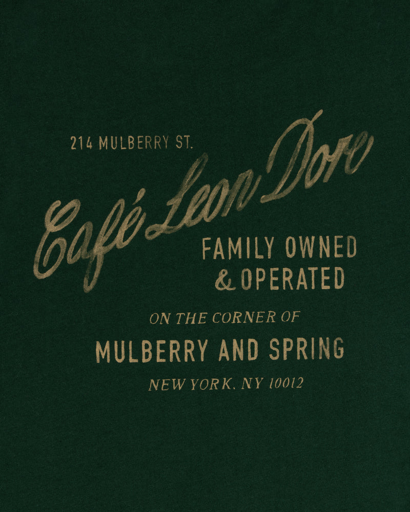 Green tee with gold text: Café Leon Dore, Family Owned & Operated, Mulberry and Spring, NYC.