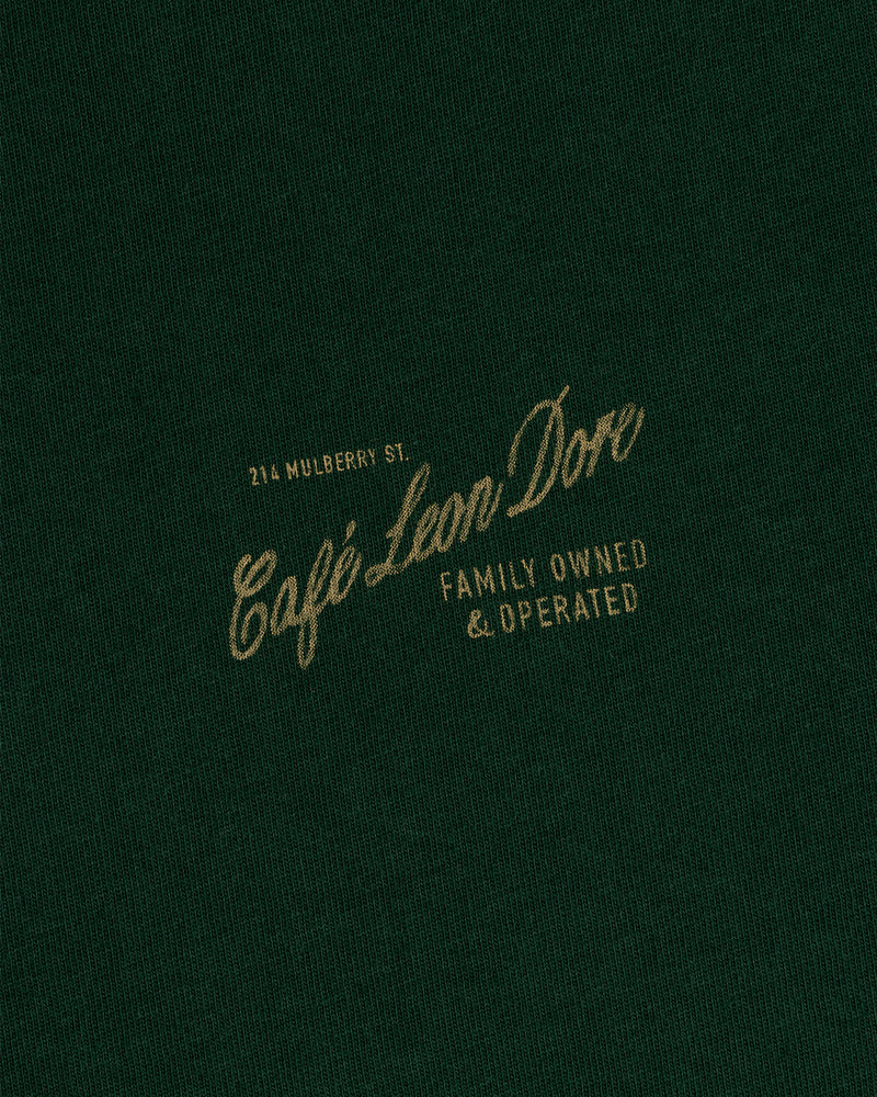 Dark green Café Leon Dore Mulberry Tee with gold text: 214 Mulberry St., Family Owned & Operated.