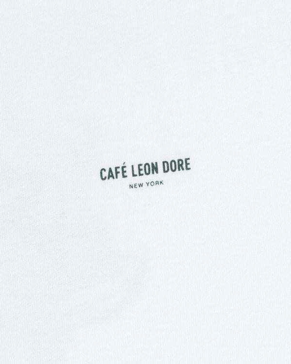 White Café Leon Dore Caricature Tee featuring small, dark “CAFÉ LEON DORE NEW YORK” print at the center.