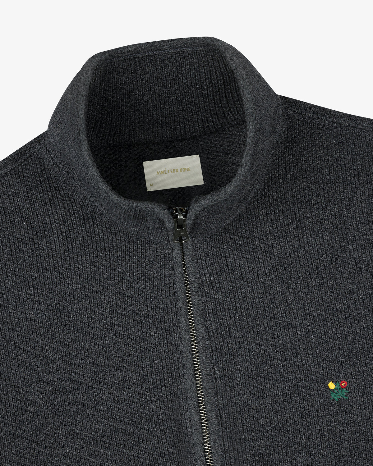 Crest Piqué Half-Zip Pullover in dark gray with ribbed texture, small embroidered flower, and visible collar label.