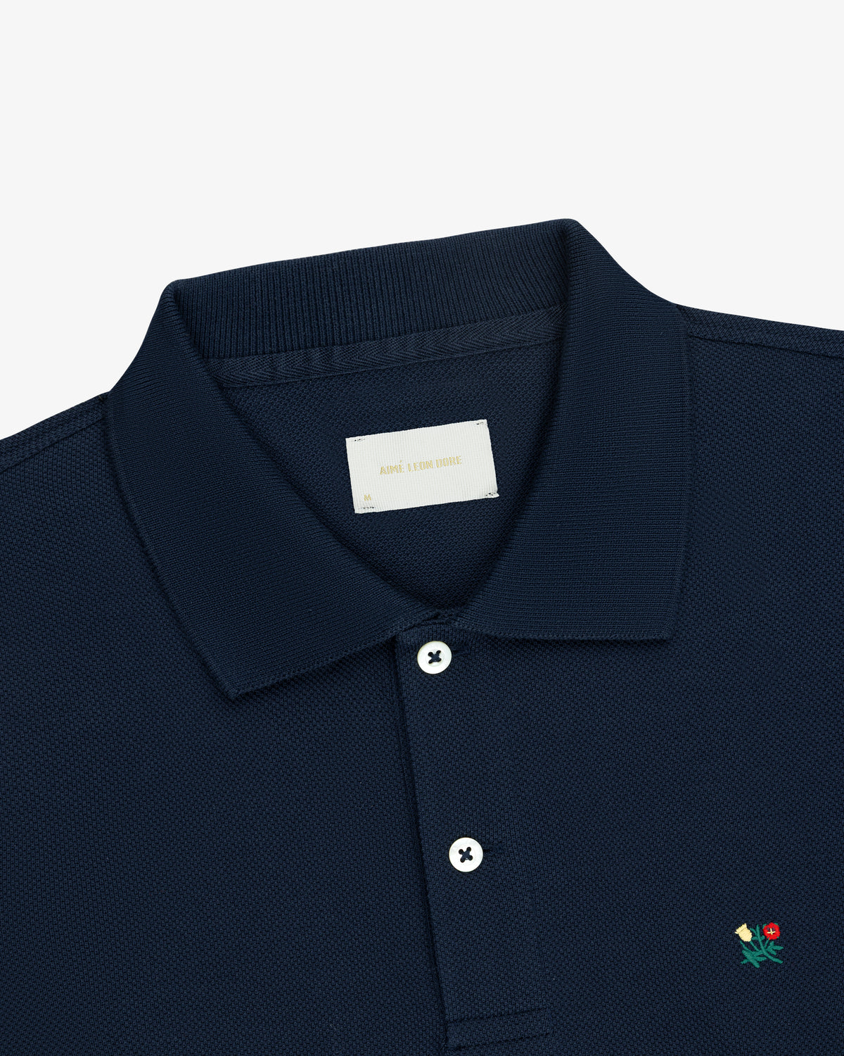 Long-Sleeve Crest Piqué Polo in navy blue with white buttons and a small flower chest embroidery, on white background.
