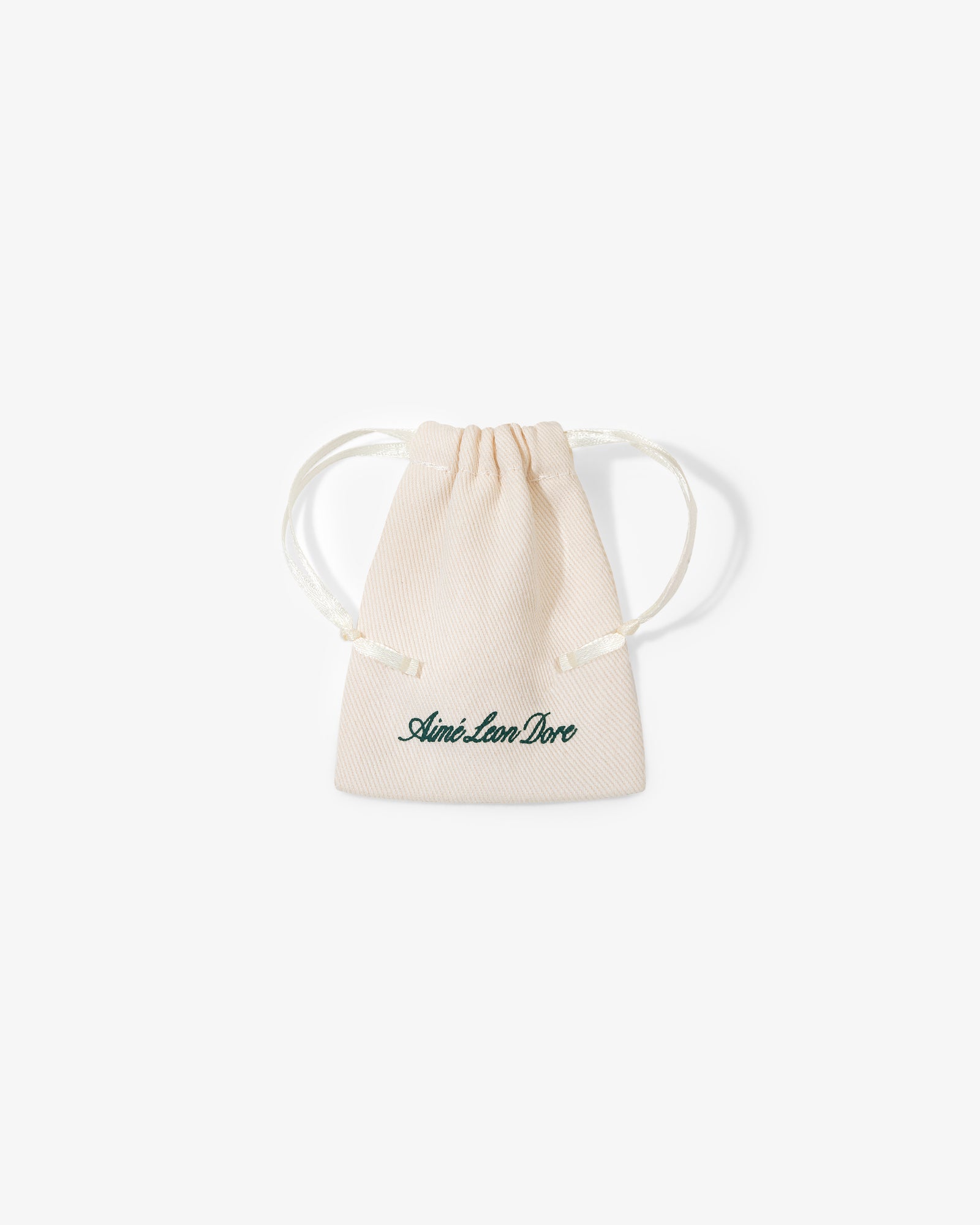 A small beige drawstring pouch with "Queens Crest Penny" written in green script on the front.