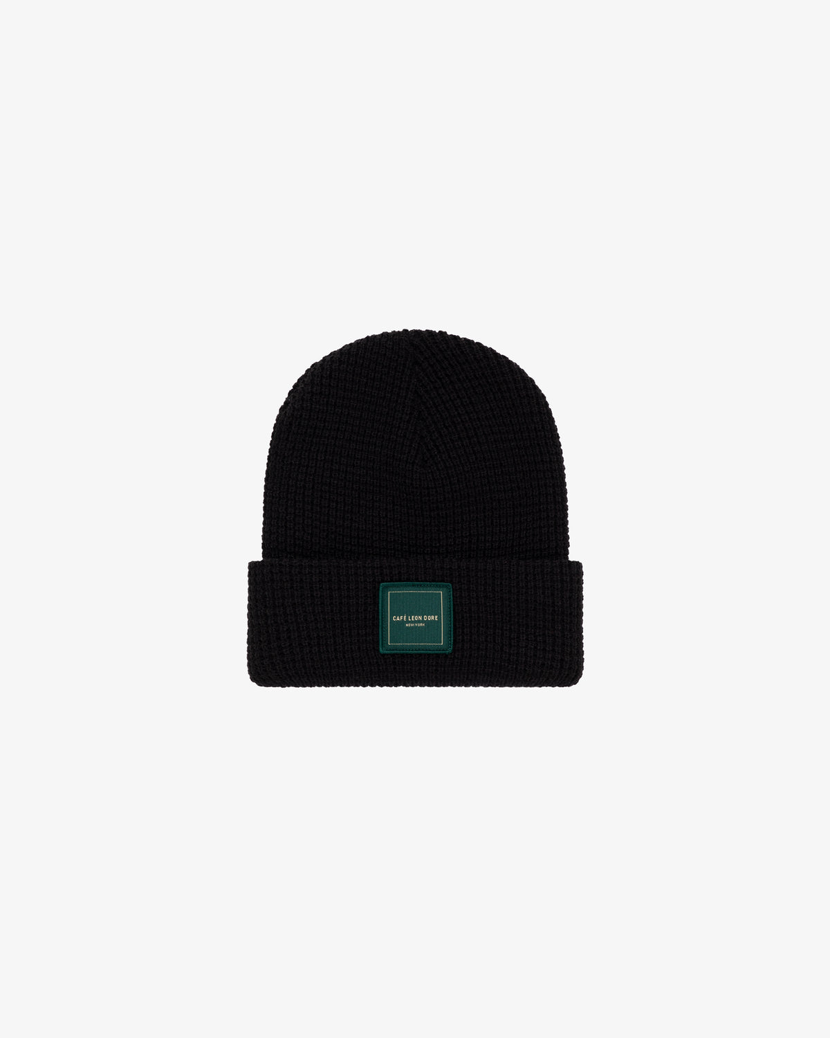 Café Leon Dore Beanie: black knit with folded brim and rectangular green patch, shown on a white background.