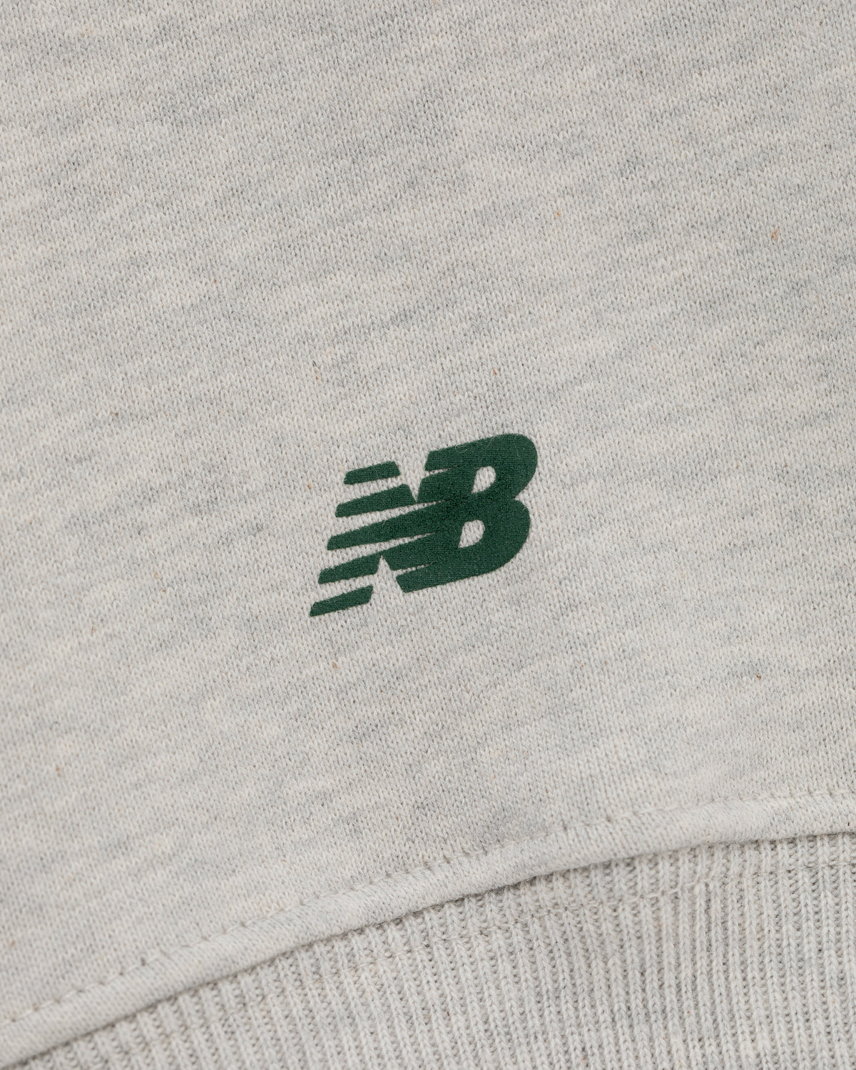 Close-up of a green New Balance logo on light grey ALD / New Balance SONNY NY IFTB Crewneck Sweatshirt.