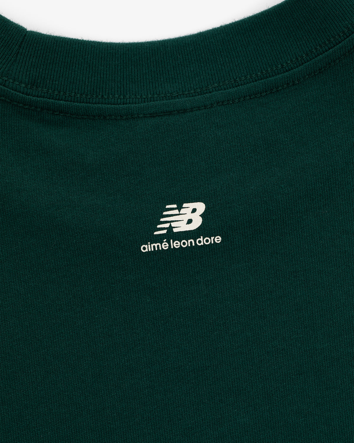 Close-up of the ALD / New Balance SONNY NY Long-Sleeve Tee in green with white logos printed below the collar on back.
