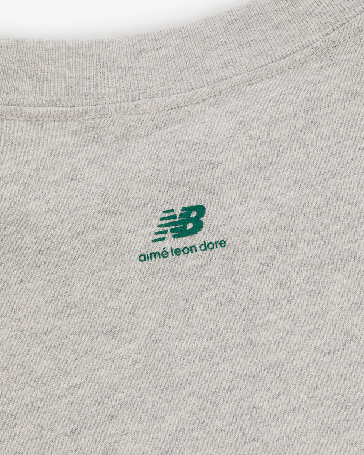 Close-up of the ALD / New Balance SONNY NY Long-Sleeve Tee with a green logo printed near the collar.