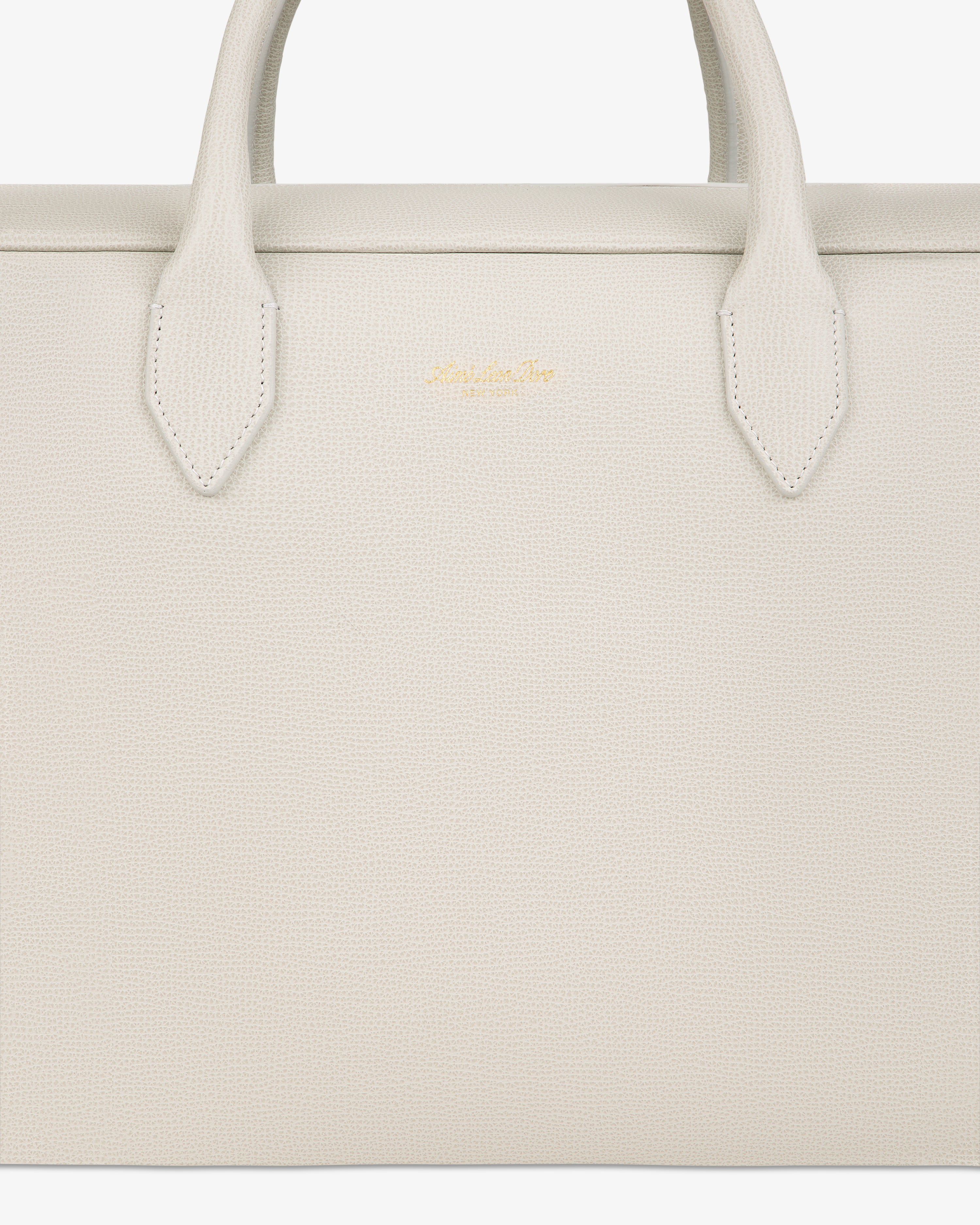 Close-up of a textured, off-white Full Grain Leather Briefcase Duffle with two handles and a small gold logo in the center.