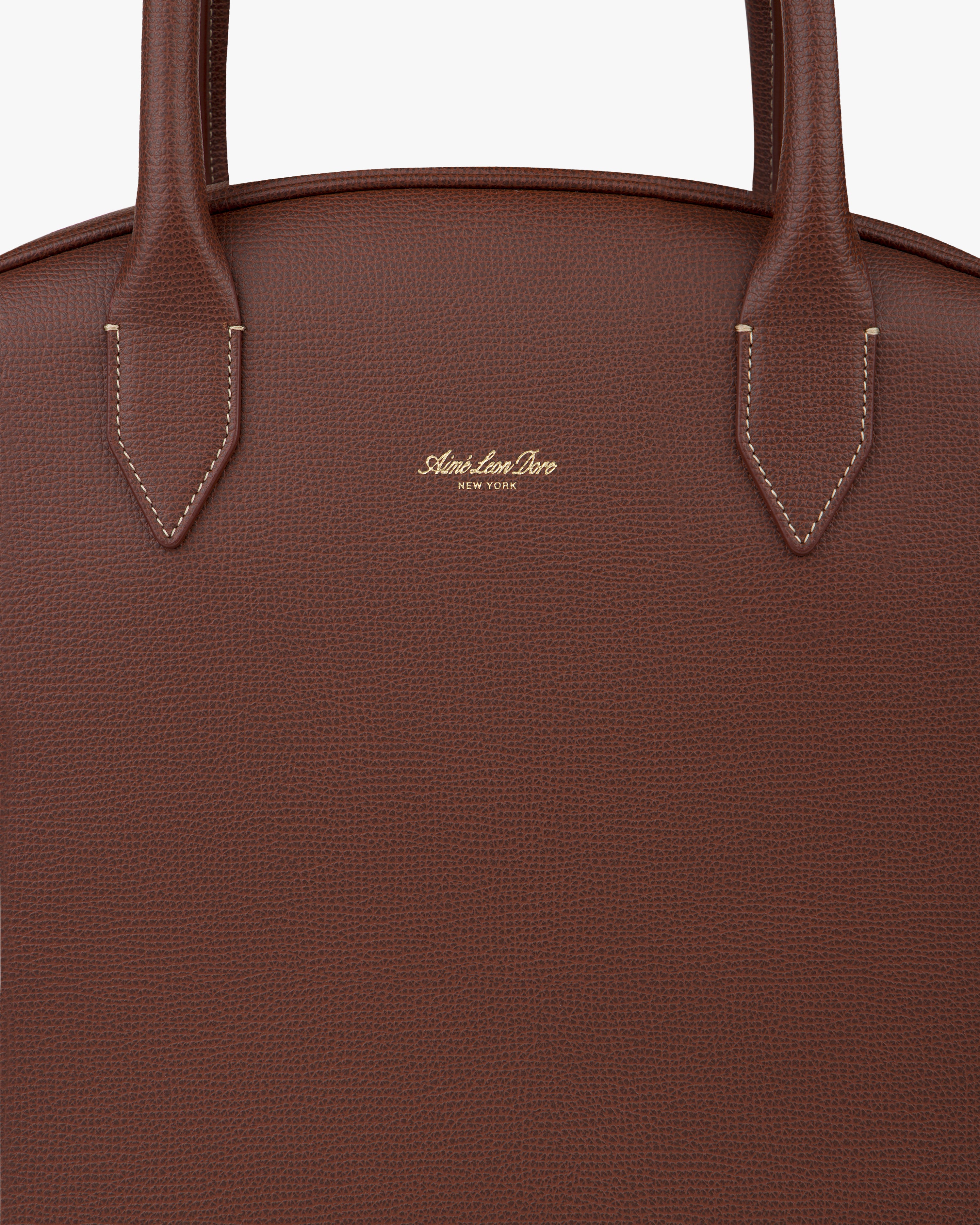 Close-up of Full Grain Leather Crescent Shoulder Bag in brown with two handles and gold embossed logo on the front.
