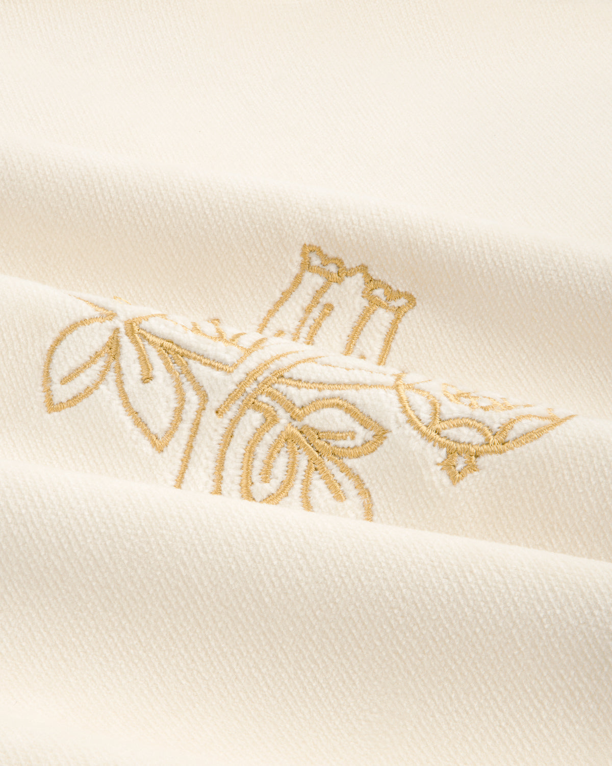 Queens Crest Throw Pillow: White fabric with gold floral embroidery and a soft, textured finish.