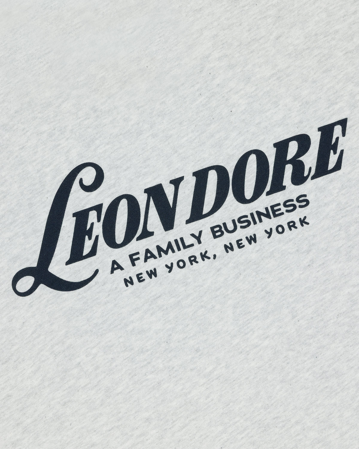 White Leon Dore Tee featuring bold black "A FAMILY BUSINESS NEW YORK, NEW YORK" text on white fabric.