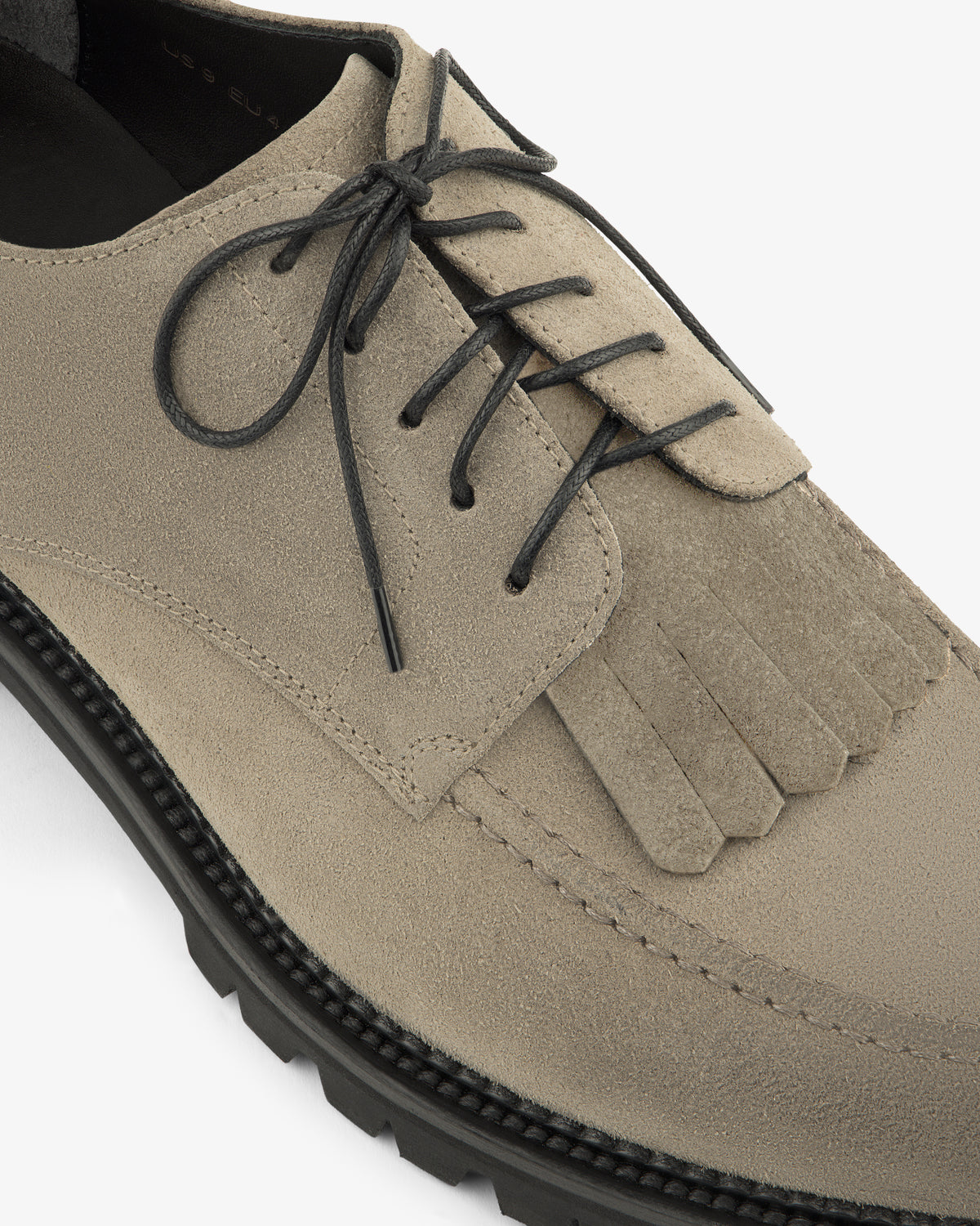 Top view of the Suede Lug Sole Derby in beige, featuring fringe detail and a contrasting black sole.