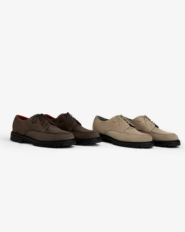 A pair of dark brown and light beige Suede Lug Sole Derby shoes, both featuring thick black lug soles.