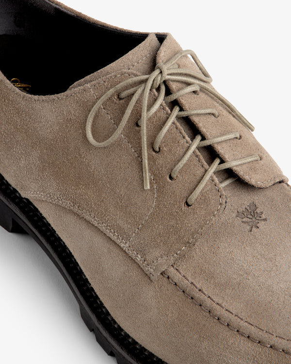 Suede Lug Sole Derby in taupe suede with a thick black lug sole and a small leaf emblem on the side.