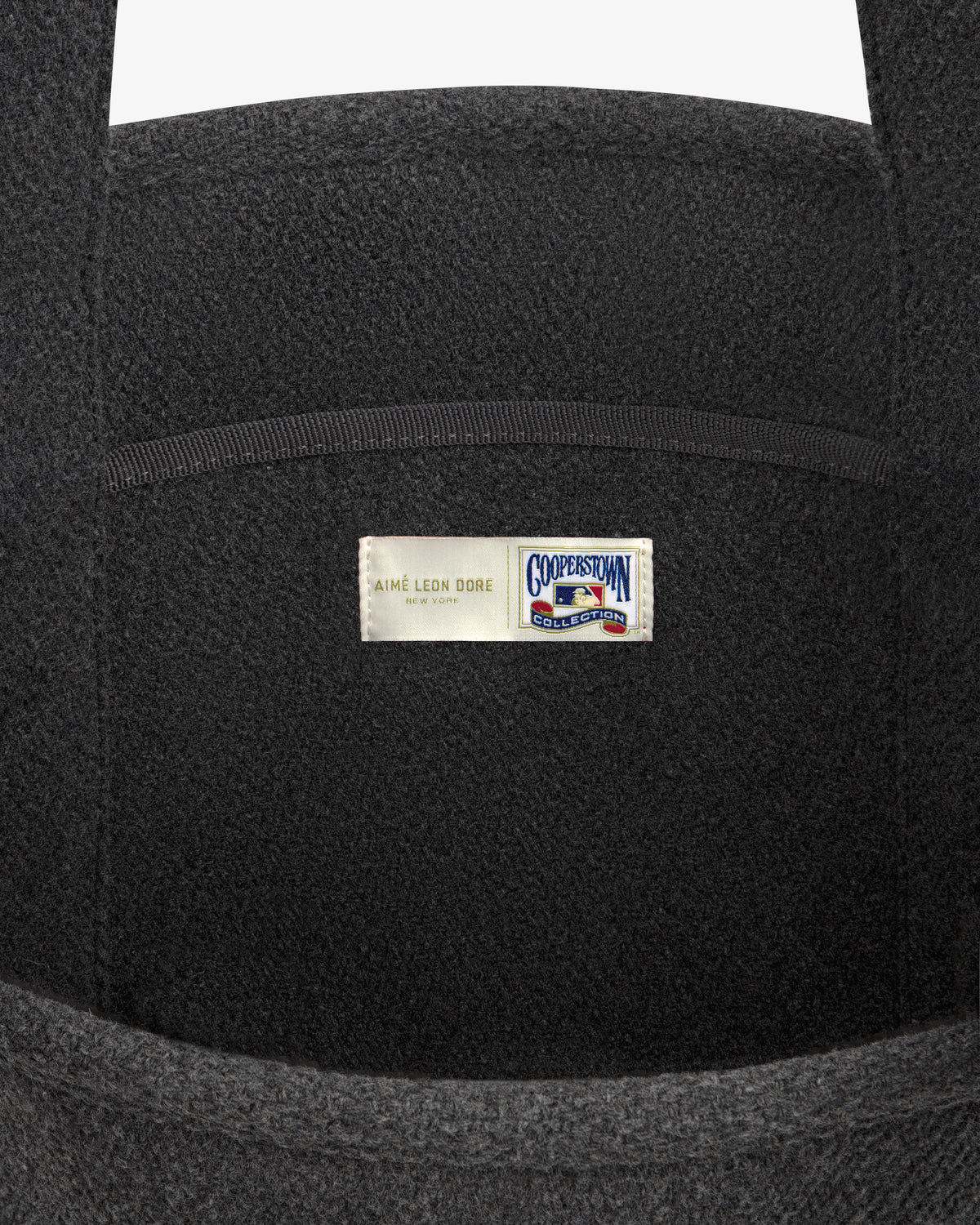 Close-up of a dark gray NY Highlanders Wool Tote Bag with a centered Aimé Leon Dore and Cooperstown Collection label.