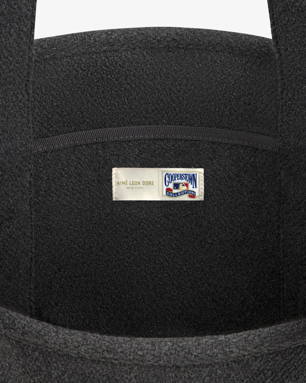 Close-up of a dark gray NY Highlanders Wool Tote Bag with a centered Aimé Leon Dore and Cooperstown Collection label.