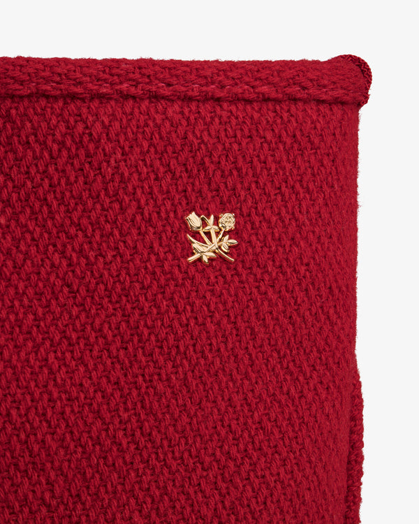 Close-up of a red NY Highlanders Wool Tote Bag featuring a small gold floral pin.