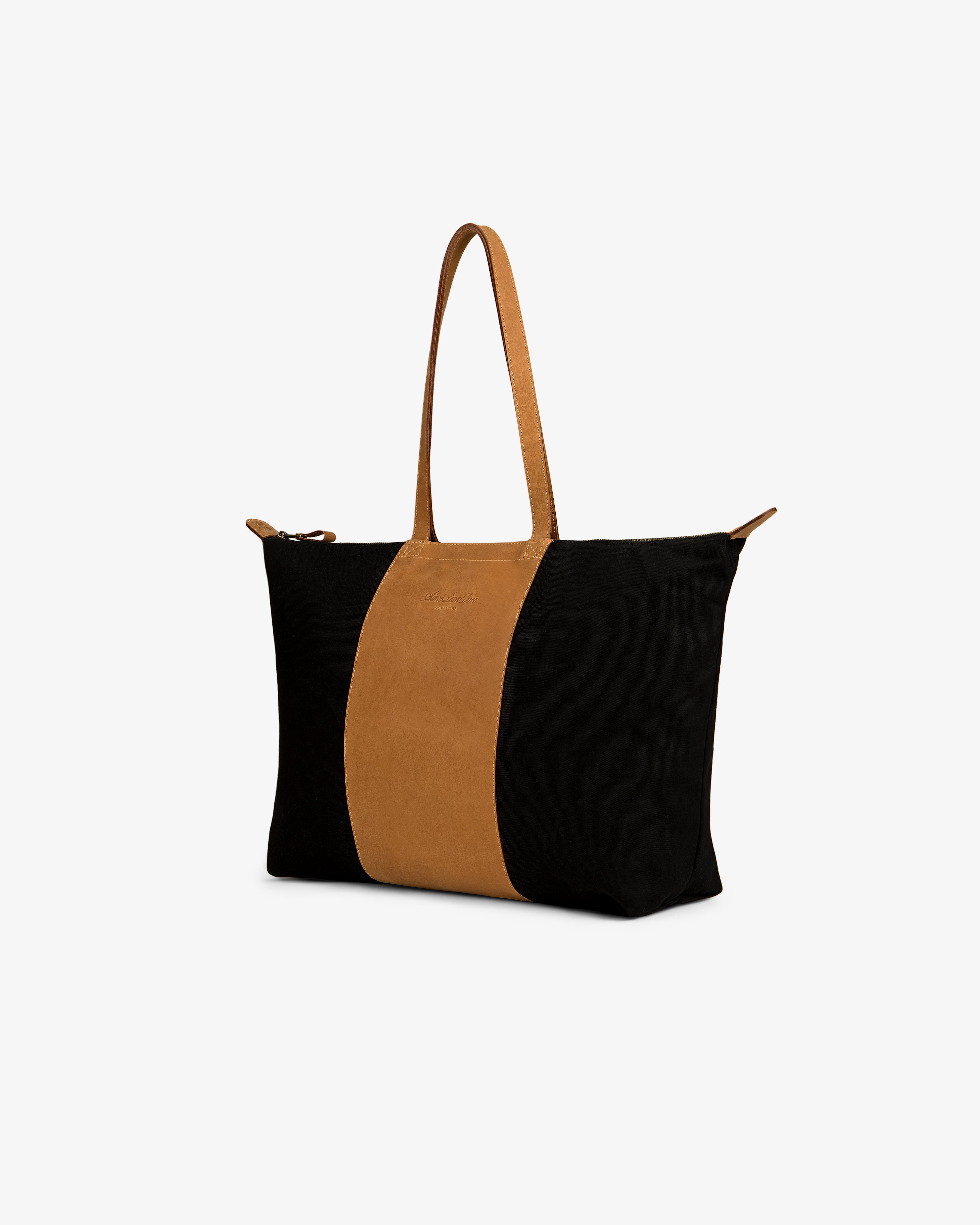Leather Canvas Zip Tote in black with brown handles and a center brown stripe, displayed on a white background.