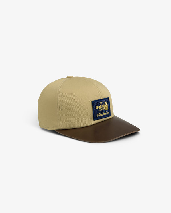 Tan ALD/North Face hat with brown leather brim and blue/yellow logo patch on front.