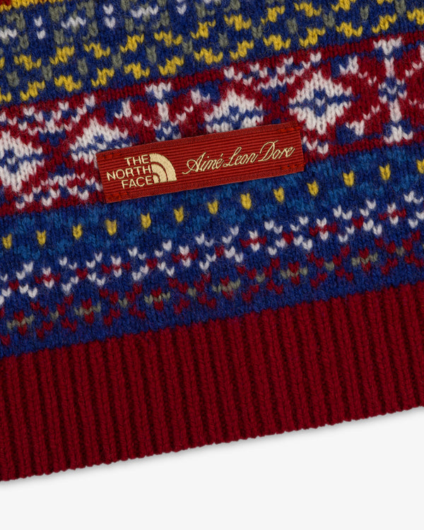 Close-up of the ALD / The North Face Fair Isle Balaclava with a brown co-branded tag on patterned knit fabric.