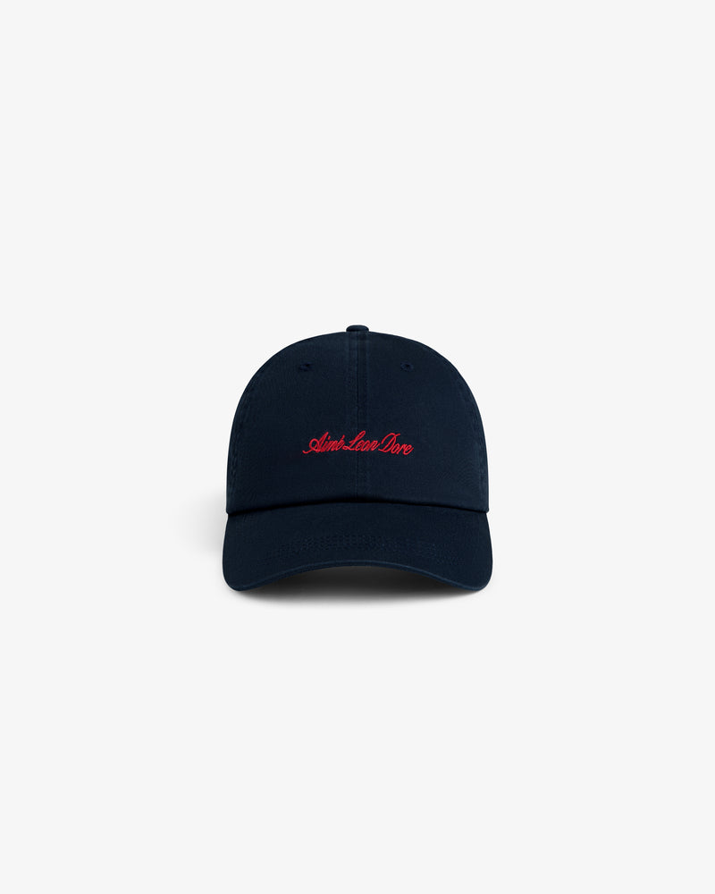 Washed Script Chino Hat in navy with Aime Leon Dore red cursive embroidery on front, shown on white background.
