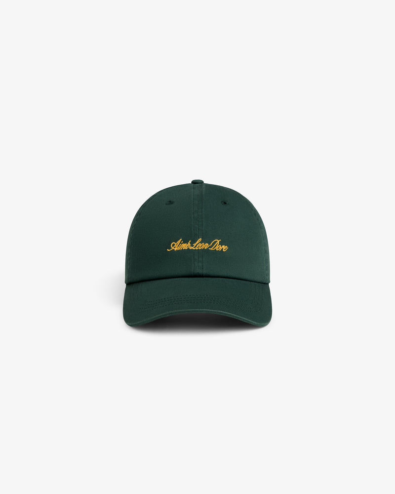 Washed Script Chino Hat in dark green with yellow Aimé Leon Dore text, displayed on a white background.