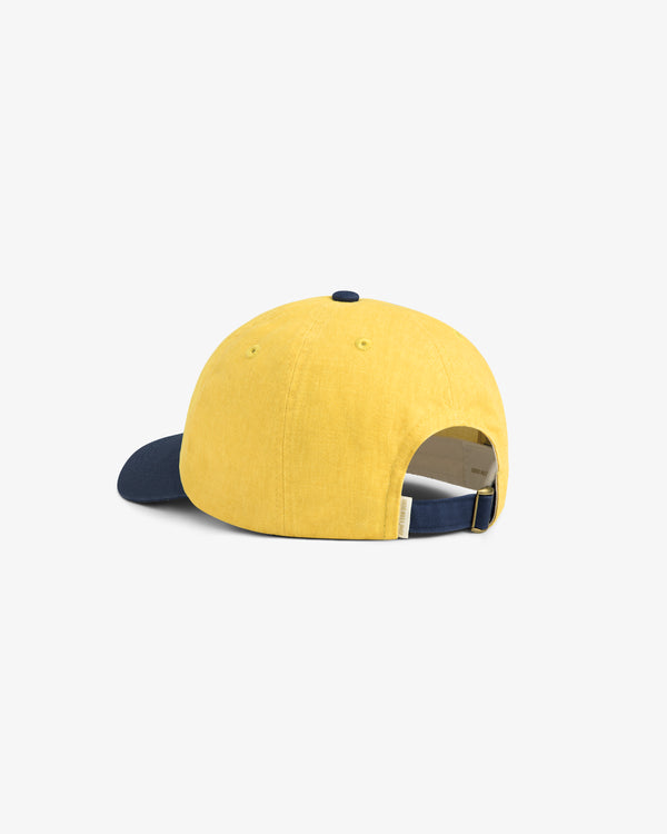 Pigment Dyed Logo Hat in yellow with navy brim, adjustable strap, shown from the back on a white background.