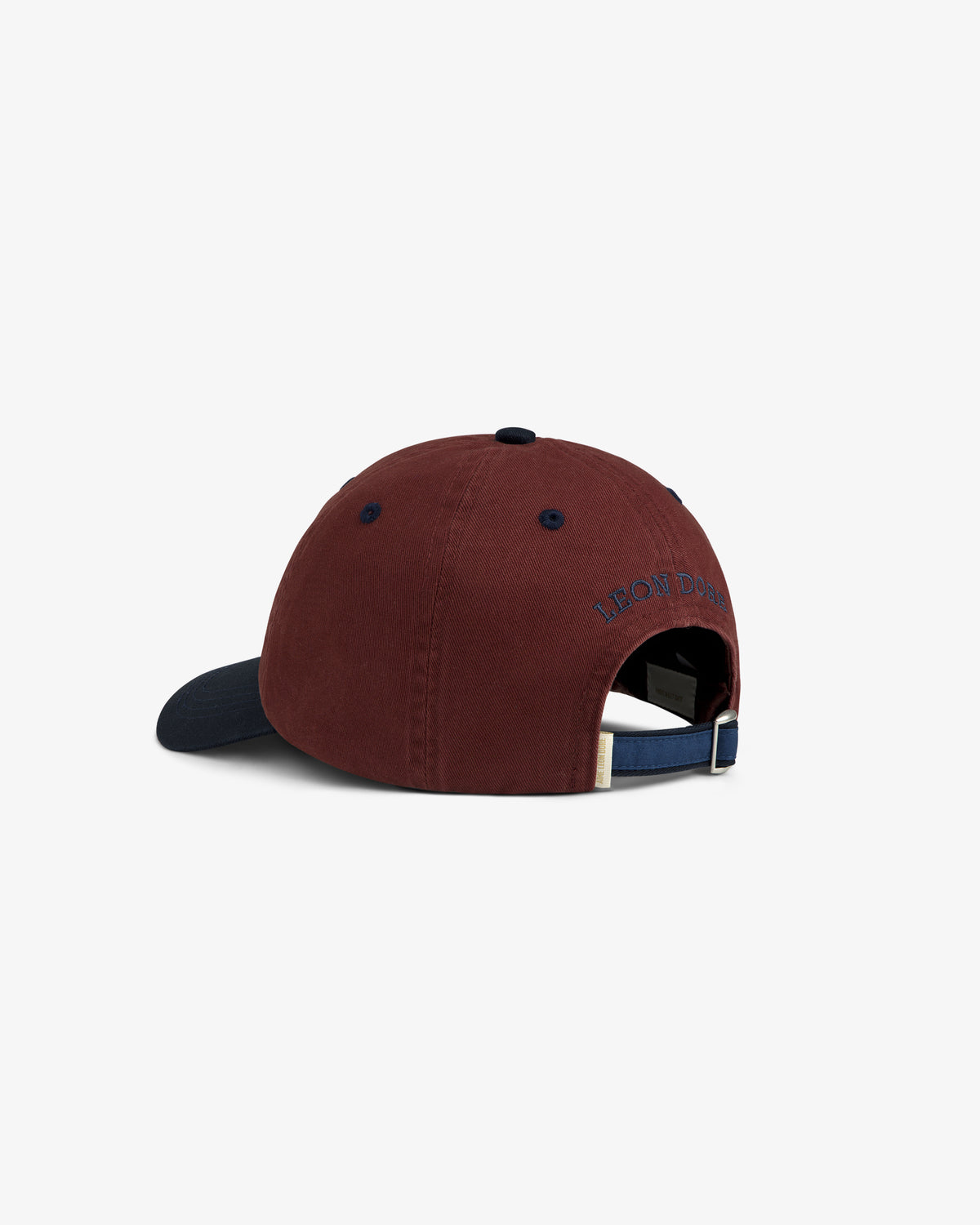 Crest Shield Hat: maroon baseball cap with navy brim, adjustable strap, and embroidered text above the back opening.