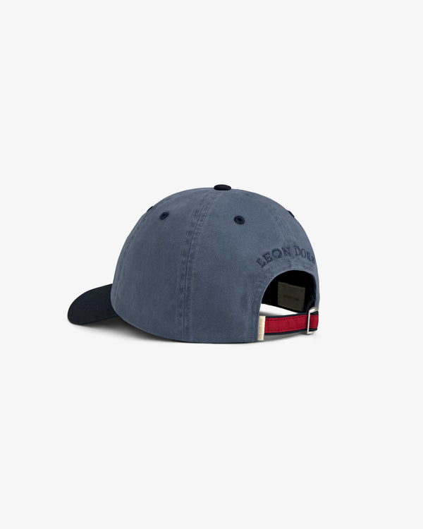 Crest Shield Hat in blue, back view with embroidered text and adjustable strap featuring a metal clasp.