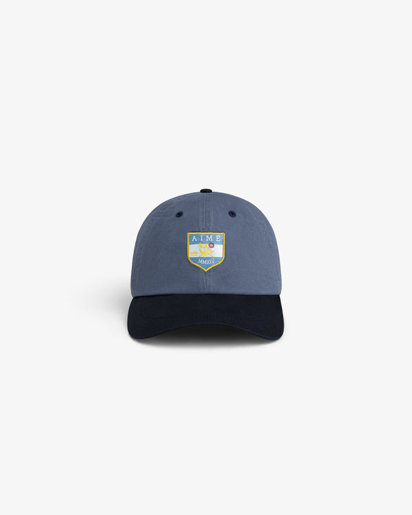 Crest Shield Hat: Blue cap with yellow and green AIME patch embroidered on the front.